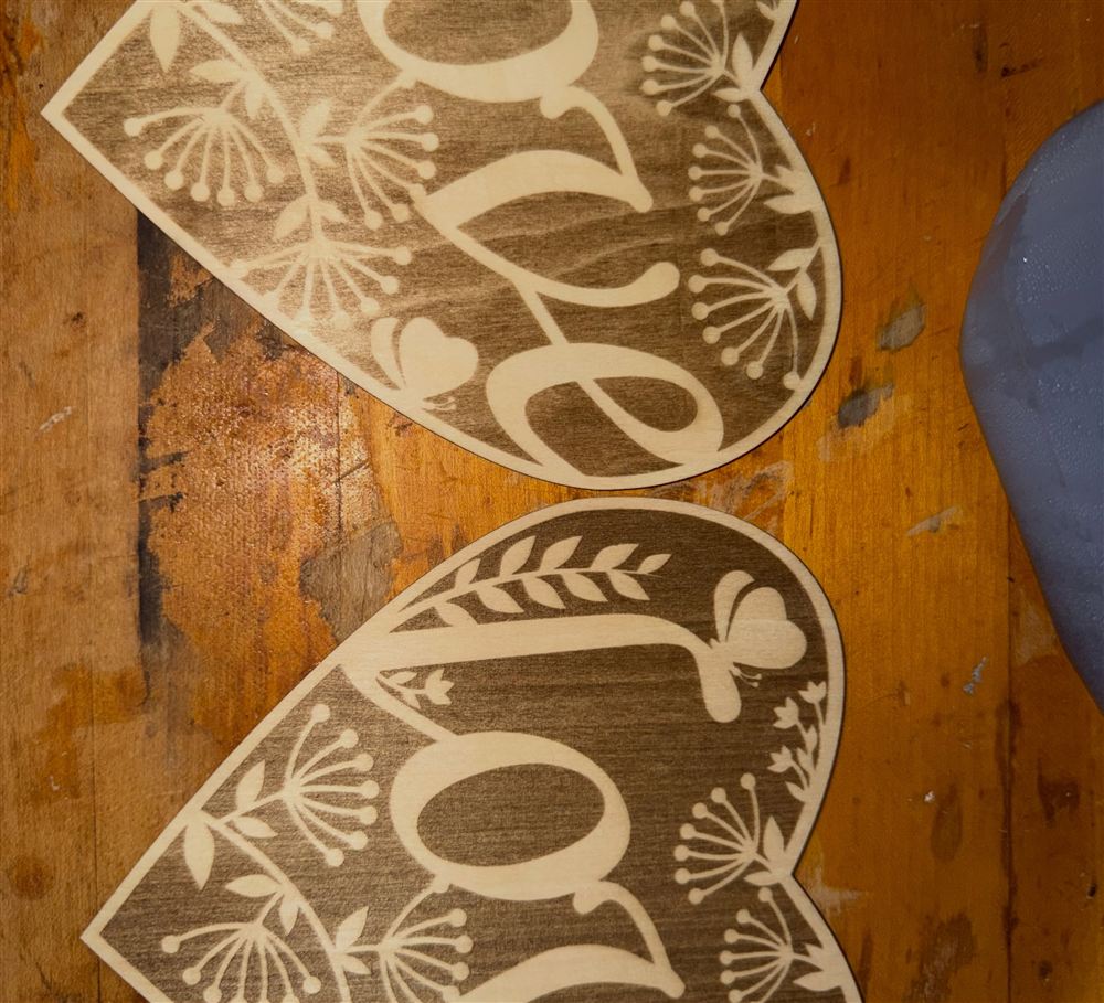Two birch hearts engraved with floral lettering