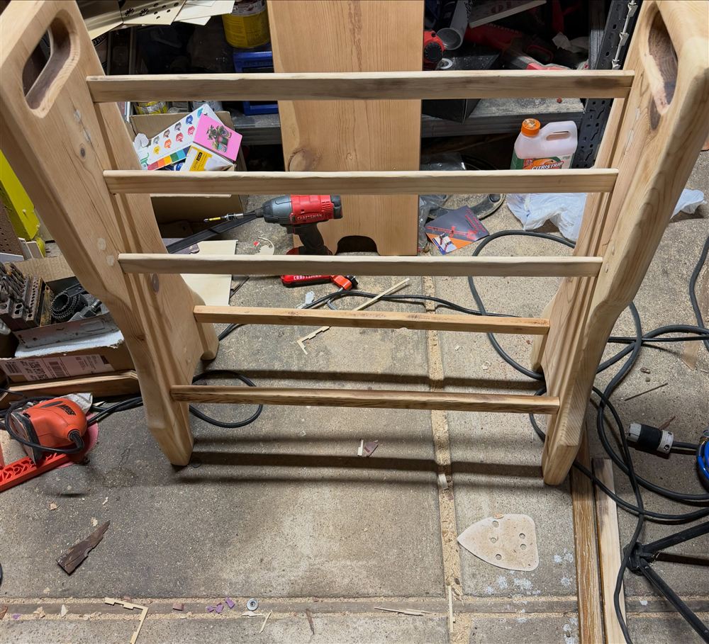 An unfinished pine quilt rack with five rails standing in the shop
