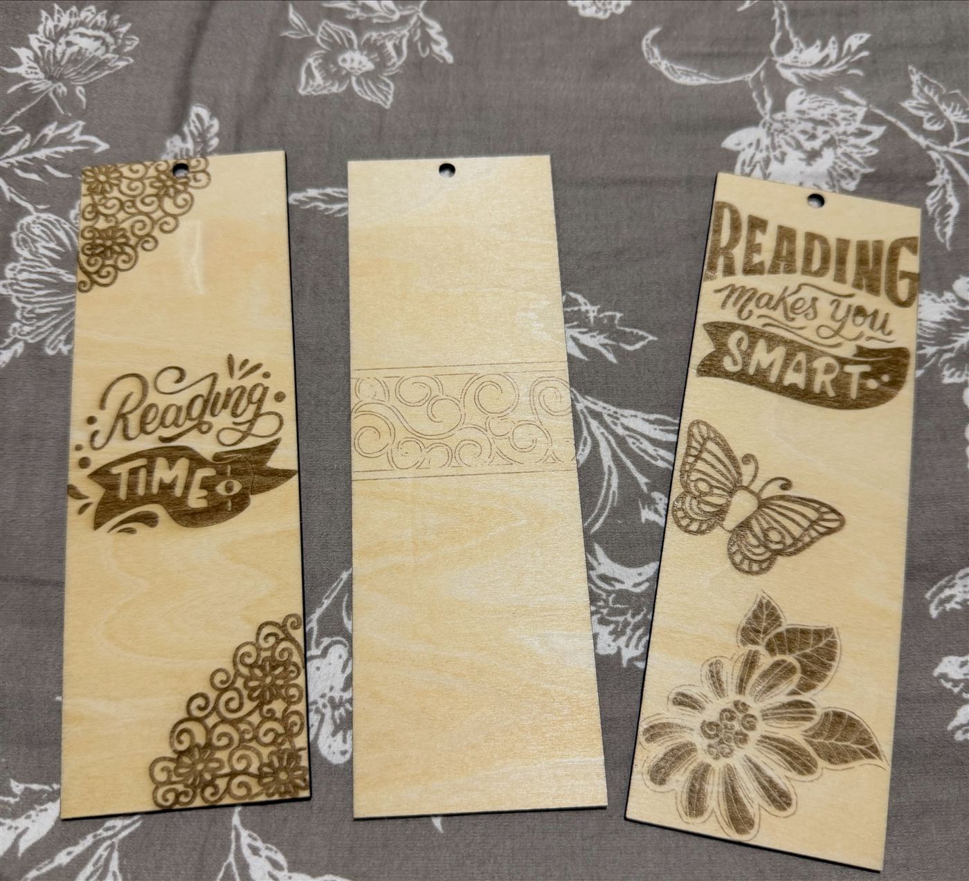 Three engraved birch bookmarks with reading quotes and floral designs