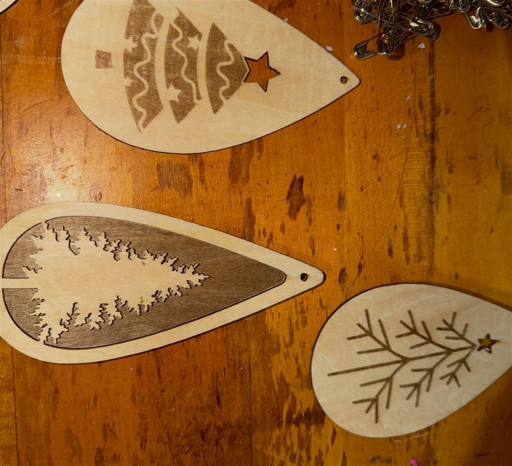 Teardrop birch ornaments engraved with different Christmas tree designs